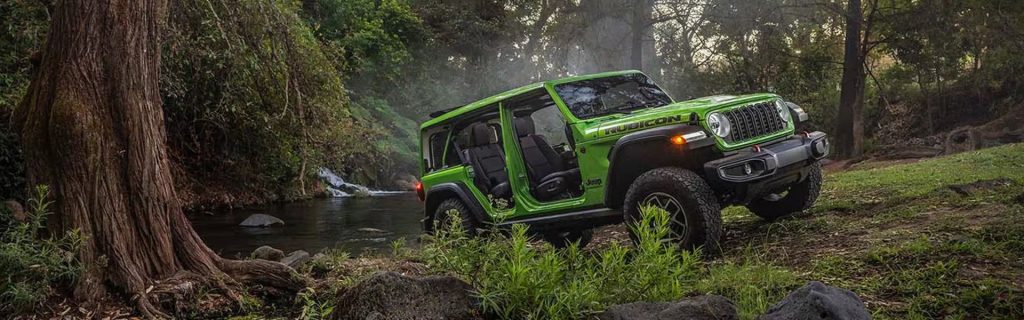 Jeep Wrangler Rubicon off-roading through forest terrain
