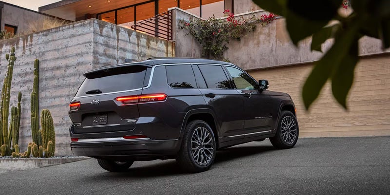 Dark gray Jeep Grand Cherokee parked outside a modern home.